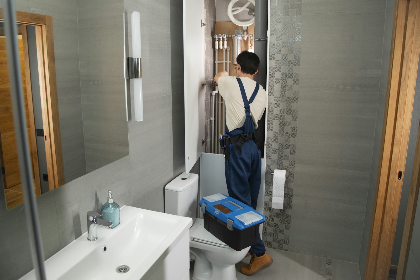 Plumber working inside a bathroom service access panel